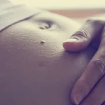 Dettaglio di donna in gravidanza con una mano sulla pancia