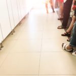 Dettaglio di gambe femminili in fila ai bagni pubblici