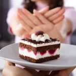 Dettaglio di due mani femminili che respingono una torta al cioccolato