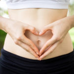 mani femminili che formano un cuore sull'ombelico