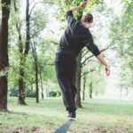 Ragazzo di spalle in un parco che è in equilibrio su una sbarra metalica