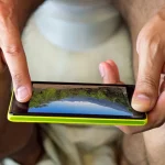 Dettaglio di un uomo seduto al water con un cellulare in mano