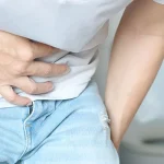 Dettaglio di un uomo con mano sulla pancia con postura dolorante