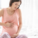 Donna in gravidanza con mano sulla pancia - dolori stipsi