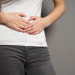 Dettaglio di mani femminili su una pancia in posizione dolorante